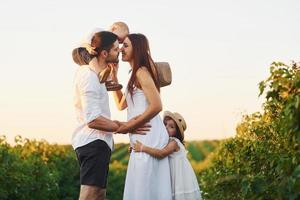 Family of four people spending free time on the field at sunny day time of summer photo