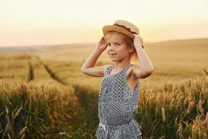 Little girl standing on the agricultural field at evening time. Conception of summer free time photo