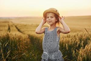 Little girl standing on the agricultural field at evening time. Conception of summer free time photo