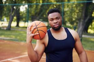 African american man standing with ball on the court outdoors photo