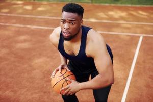hombre afroamericano juega baloncesto en la cancha al aire libre foto