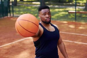 African american man standing with ball on the court outdoors photo