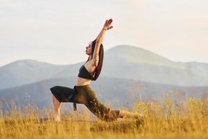 hermosa joven haciendo ejercicios de yoga. majestuosas montañas de los cárpatos. hermoso paisaje de naturaleza virgen foto