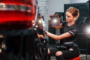 Final polishing. Modern black automobile get cleaned by woman inside of car wash station photo