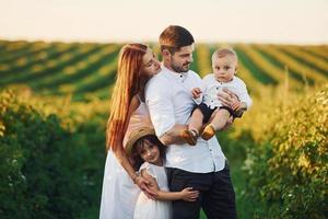 Father, mother with daughter and son spending free time outdoors at sunny day time of summer photo