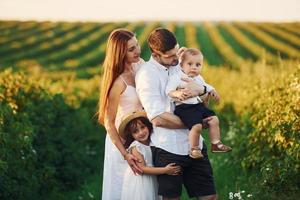 Father, mother with daughter and son spending free time outdoors at sunny day time of summer photo