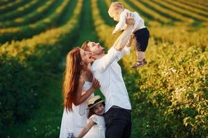 Father, mother with daughter and son spending free time outdoors at sunny day time of summer photo