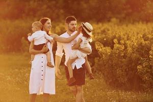 luz solar bu iluminada. familia de cuatro personas que pasan tiempo libre en el campo durante el día de verano foto