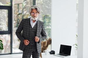 hombre de negocios en la oficina. Senior hombre moderno con estilo con pelo gris y barba en el interior foto
