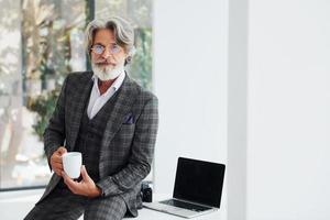 Businessman in the office. Senior stylish modern man with grey hair and beard indoors photo