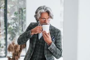 Businessman in the office. Senior stylish modern man with grey hair and beard indoors photo