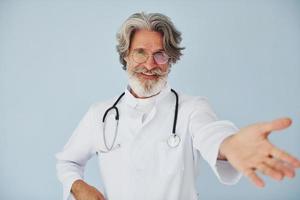 médico positivo profesional. Senior hombre moderno con estilo con pelo gris y barba en el interior foto