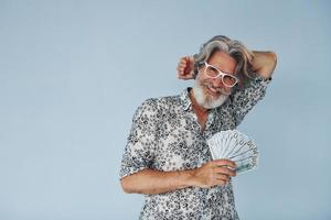 Millionaire with cash in hands. Senior stylish modern man with grey hair and beard indoors photo