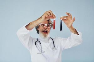 Doctor holds test tubes. Senior stylish modern man with grey hair and beard indoors photo