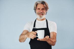 camarero con bebidas en las manos. Senior hombre moderno con estilo con pelo gris y barba en el interior foto