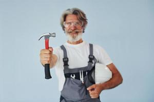 reparador listo para trabajar. Senior hombre moderno con estilo con pelo gris y barba en el interior foto