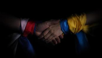 Russian flag and Ukraine flag in hands showing symbol of struggle war photo