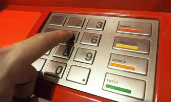 Automatic teller machine or ATM pin button close-up and human hand index finger pushing keypad for withdrawal the money by private personal password banking. photo