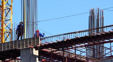 obra de construcción y trabajador de pie sobre material de acero y hormigón y cielo azul. foto