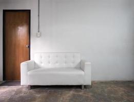 White leather sofa and white old wall and old wood door in room. photo