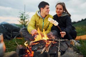 Classical marshmallow making near campfire. Young couple. Majestic Carpathian Mountains. Beautiful landscape of untouched nature photo