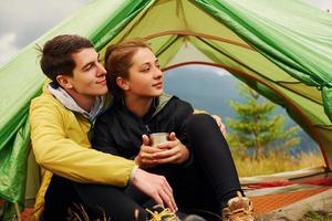 Guy with his girlfriend sits near tent. Majestic Carpathian Mountains. Beautiful landscape of untouched nature photo