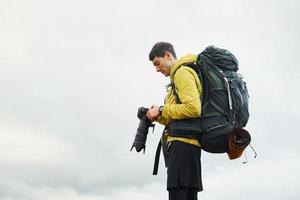 joven fotógrafo masculino con su cámara profesional tomando fotos de la hermosa naturaleza