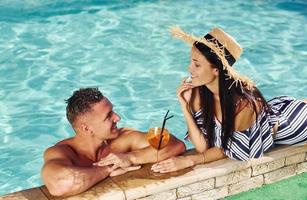 pareja alegre o amigos juntos en la piscina de vacaciones foto