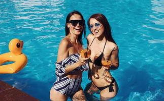 Happy female friends having fun outdoors in swimming pool photo