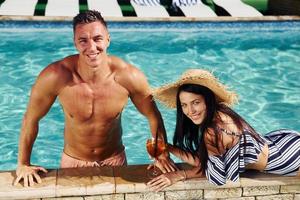 Cheerful couple or friends together in swimming pool at vacation photo