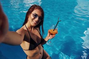 Girl in sunglasses have fun and rest in swimming pool at daytime photo