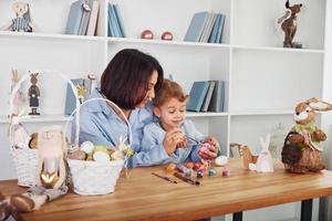 Mother with daughter celebrating Easter holidays together. Paints eggs photo