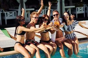 Group of young happy people have fun in swimming pool at daytime photo