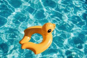 Top view of yellow duck toy for swimming in the pool at daytime photo