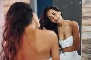 Beautiful young woman standing in bathroom near the mirror photo