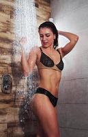 guapa morena con cuerpo delgado sexy en ropa interior tomando una ducha en el spa foto