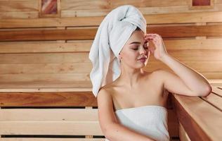 Young beautiful woman in white towel have a rest in the sauna. Conception of bodycare photo