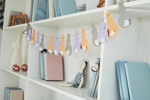 Close up view of shelves with books and Easter toy indoors at home photo