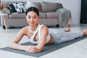 Lying down on the mat and taking a break. Young woman with slim body shape in sportswear have fitness day indoors at home photo