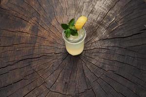 With lemon and mint. Close up view of fresh summer alcoholic cocktail on the wooden table photo