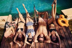 Taking a rest together. Group of young happy people have fun in swimming pool at daytime photo