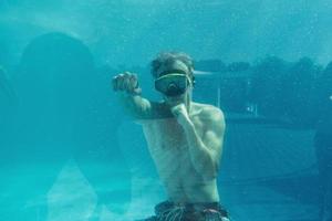 Man swimming underwater in the pool at daytime. Having fun photo