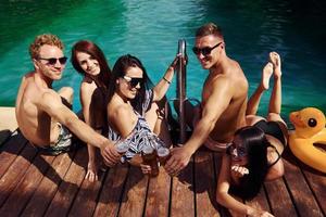 Taking a rest together. Group of young happy people have fun in swimming pool at daytime photo