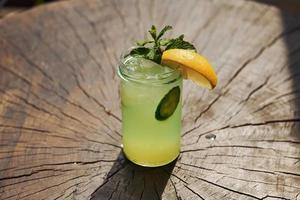 With lemon and mint. Close up view of fresh summer alcoholic cocktail on the wooden table photo