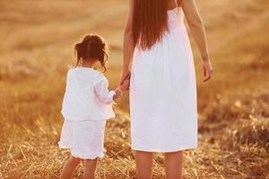 Happy mother with her little daughter spending time together outdoors on the field photo