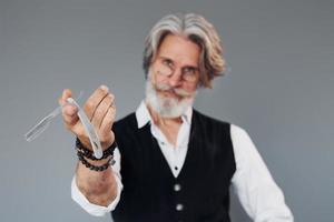 Barbershop tools. Against grey background. Stylish modern senior man with gray hair and beard is indoors photo