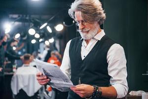 leyendo el periódico. un anciano moderno y elegante con pelo gris y barba está en el interior foto