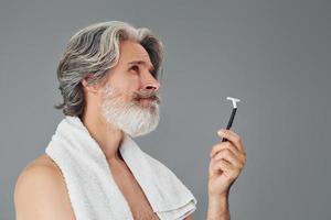 concepción del afeitado. un anciano moderno y elegante con cabello gris y barba está en el interior foto