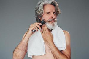 cuidando la barba. un anciano moderno y elegante con cabello gris está adentro foto
