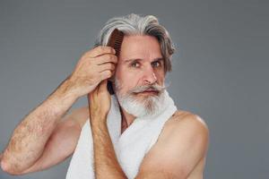 cuidando el rostro y la claridad de la piel. un anciano moderno y elegante con pelo gris y barba está en el interior foto